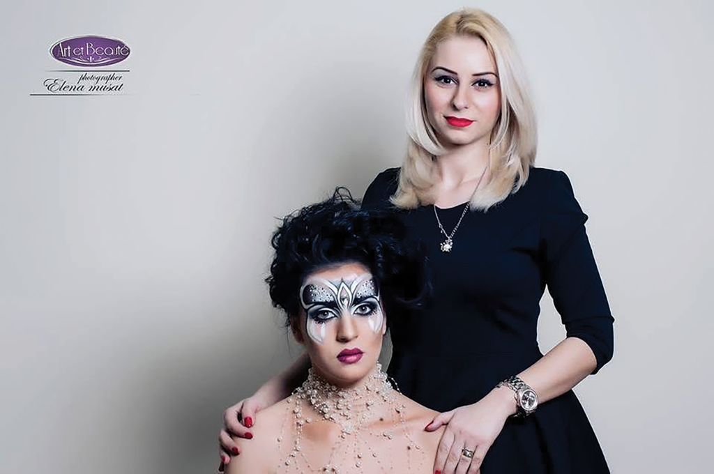 Nicoleta Streja, fondatoarea VogueLash Academy din Reading, Marea Britanie, îmbrăcată într-un sacou roșu și ținând pensule de machiaj în mână.